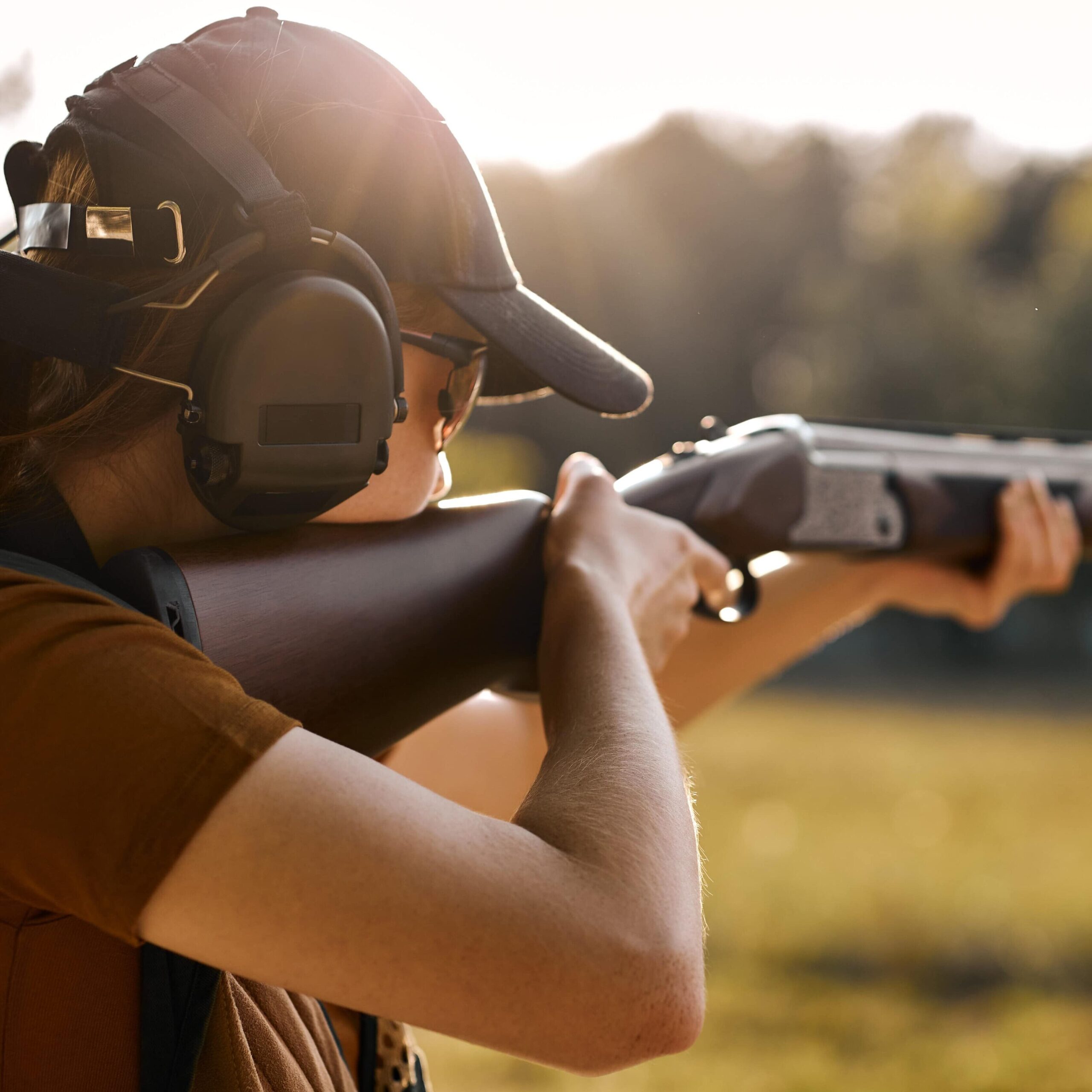 Frau mit Waffe und Gehörschutz zielt auf etwas